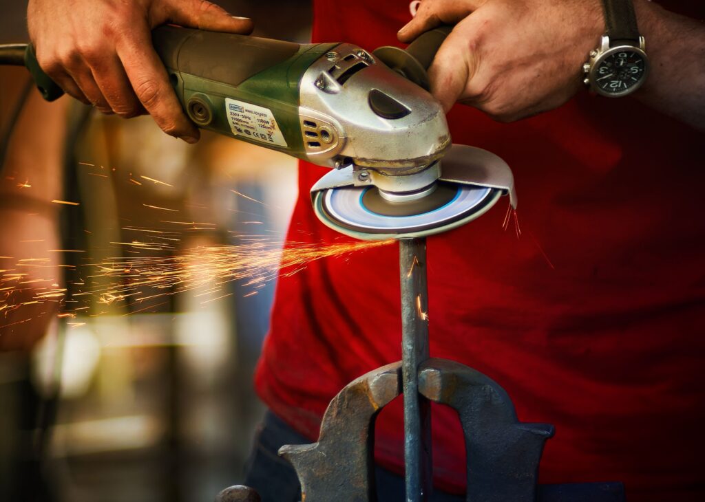 Close-up of a worker using an angle grinder with sparks flying, showcasing precision and craftsmanship.