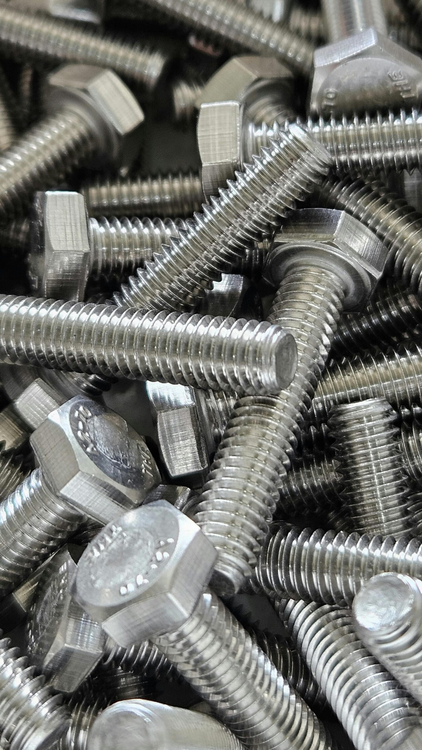 Detailed image of numerous shiny steel hex bolts, ideal for industrial use.